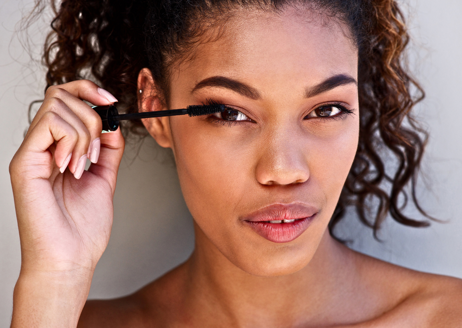 Close-up of a woman applying mascara to her eyelashes to enhance eye definition and volume