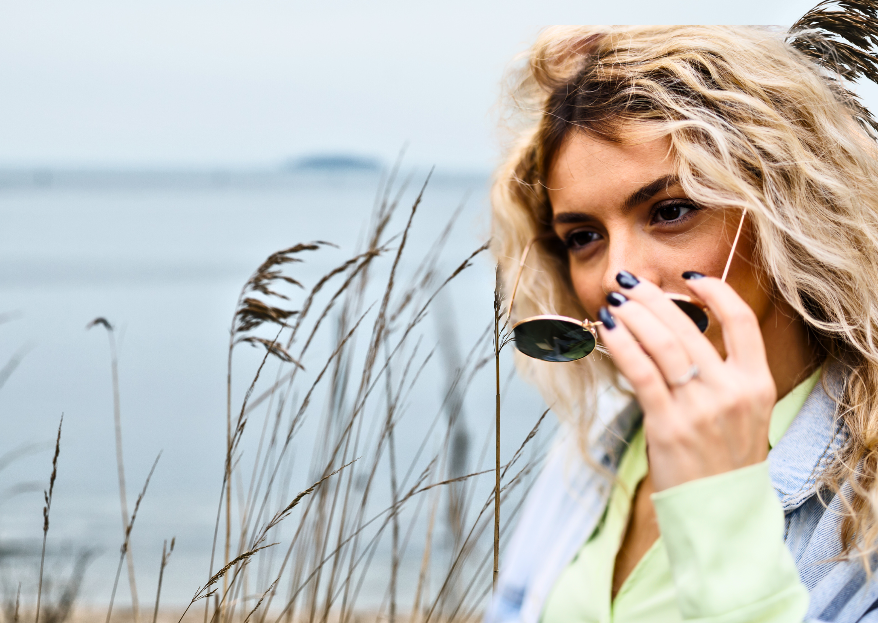 Close-up of a woman putting on sunglasses to protect her eyes and the delicate skin around them from UV damage