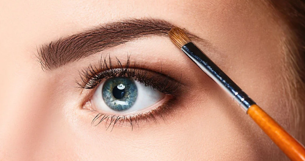 woman defining her eyebrows with an eyebrow brush to achieve a well-groomed and polished look.